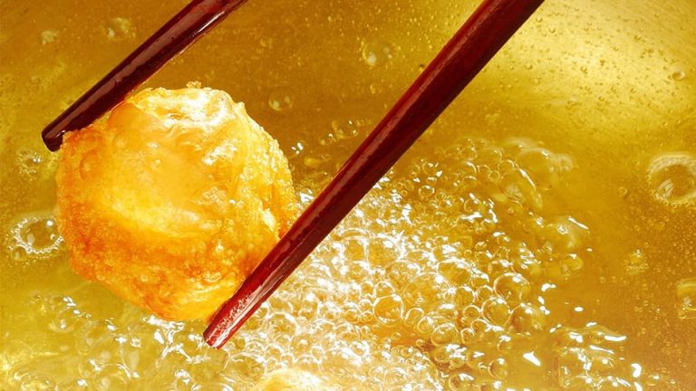 Donut being dried in vegetable oil