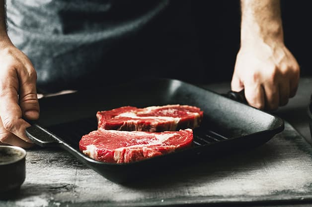 Red meat being pan fried with oils