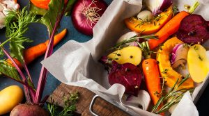 Assortment of vegetable which includes beets, carrots, onions, and potatoes, along with herbs like rosemary and thyme.
